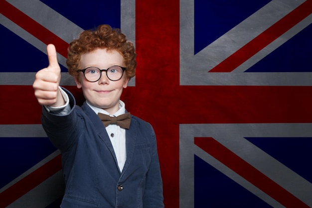 Glücklicher junger Schüler mit der britischen Flagge im Hintergrund Englisch lernen