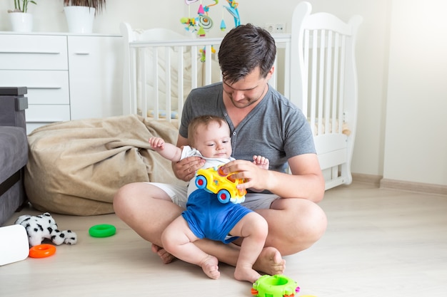 Glücklicher junger Vater, der mit seinem Kleinkindsohn auf dem Boden spielt