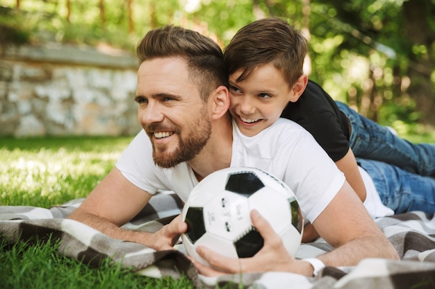 Glücklicher junger Vater mit seinem kleinen Sohn mit Fußball