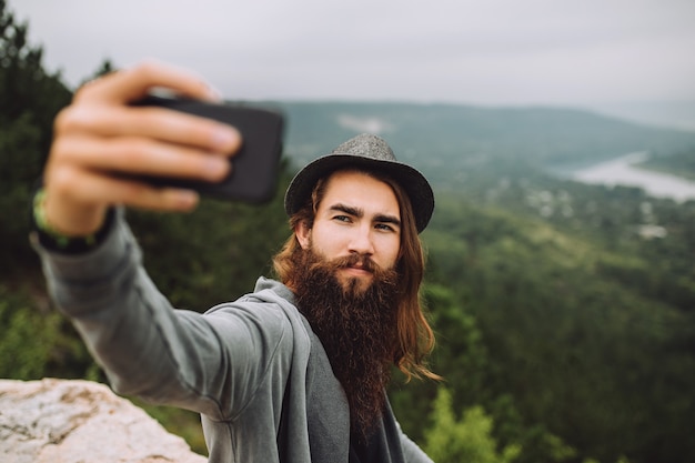 Glücklicher Kerl auf Hochgebirge mit einem Handy macht ein Selfie.