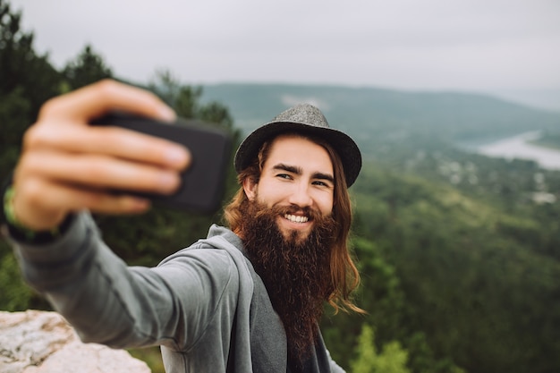 Glücklicher Kerl auf Hochgebirge mit einem Handy macht ein Selfie.