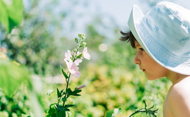 Glücklicher Kinderjunge im Panamahut, der Luft riecht, die Blumen riecht