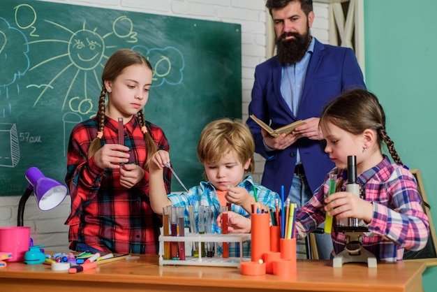 Glücklicher Kinderlehrer, der Experimente mit Flüssigkeiten im Chemielabor durchführt