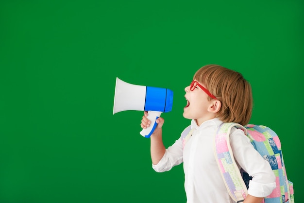 Glücklicher Kinderstudent gegen grüne Tafel