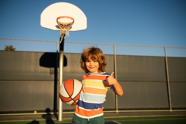 Glücklicher kleiner Junge, der Basketball auf dem Spielplatz spielt