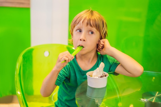 Glücklicher kleiner Junge, der ein leckeres Eis oder gefrorenen Joghurt isst