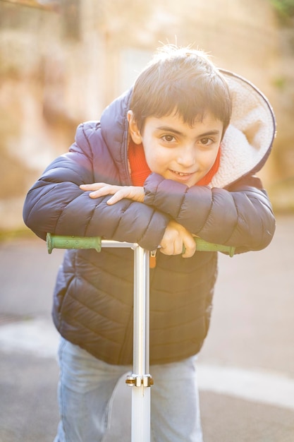 Foto glücklicher kleiner junge, der im winter roller fährt