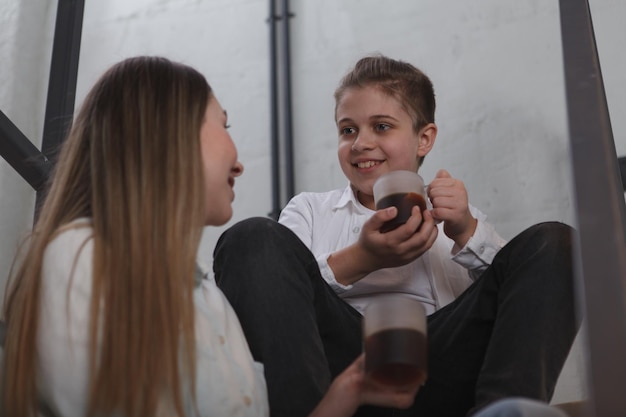 Glücklicher kleiner Junge, der mit seiner Mutter bei einer Tasse Tee spricht