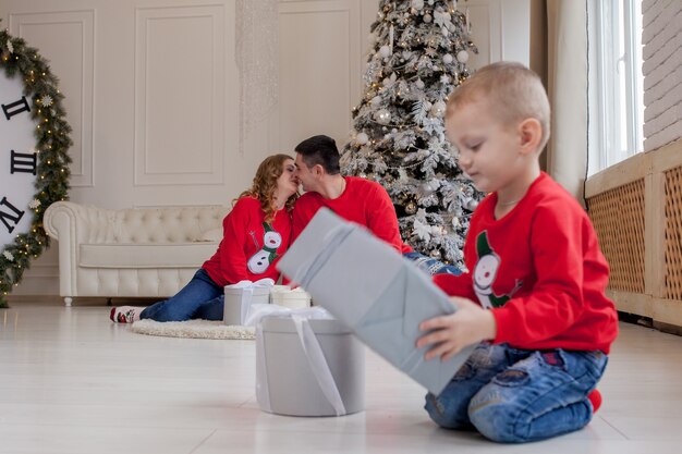 Glücklicher kleiner Junge, der Weihnachtsgeschenke öffnet