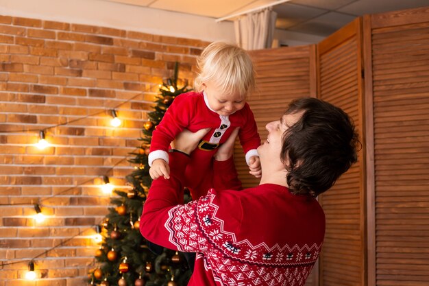 Glücklicher kleiner Junge und Vater im festlich dekorierten Raum zu Weihnachten