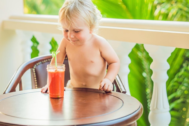 Glücklicher Kleinkindjunge, der gesunden selbstgemachten Smoothie trinkt