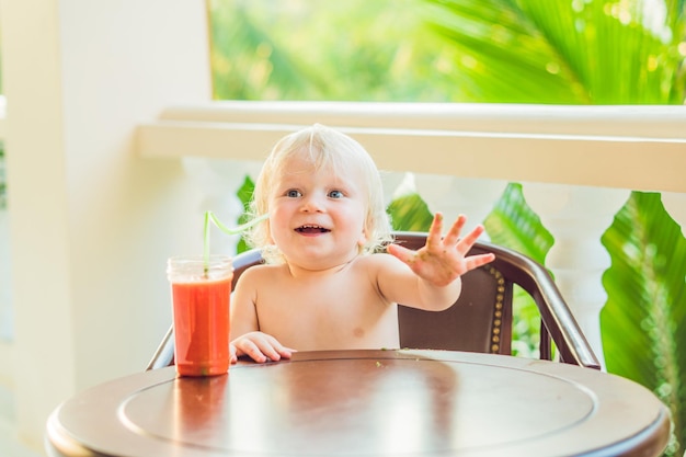 Glücklicher Kleinkindjunge, der gesunden selbstgemachten Smoothie trinkt