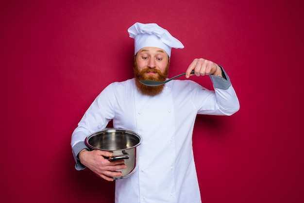 Glücklicher Koch mit Bart und roter Schürze ist bereit zu kochen