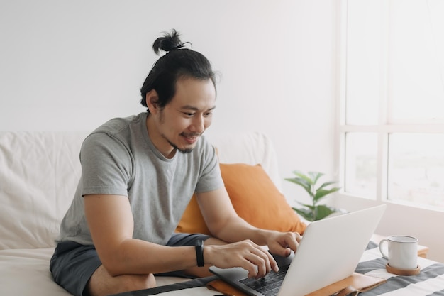 Glücklicher kreativer Mann arbeitet am Laptop in seiner Home-Office-Wohnung