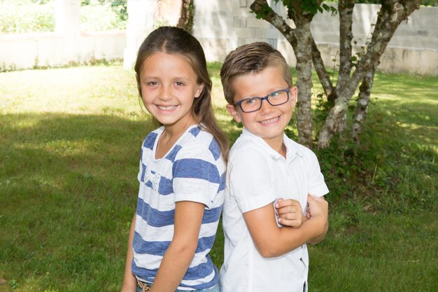 Glücklicher lächelnder Bruder und Schwester im grünen Garten des Sommers