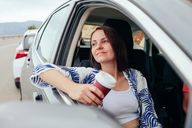 Glücklicher lächelnder Passagier der jungen Frau, der Kaffee zum Mitnehmen trinkt