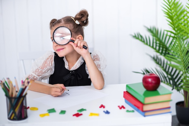 Glücklicher lächelnder Schüler am Schreibtisch im Klassenzimmer mit Stiften und Büchern