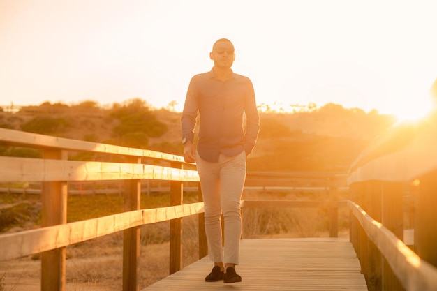 Glücklicher lateinamerikanischer Mann, der spazieren geht und den Sonnenuntergang mit Blick auf die natürliche Landschaft genießt. Warmes natürliches Licht.