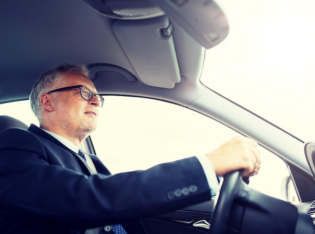 glücklicher leitender Geschäftsmann, der ein Auto fährt