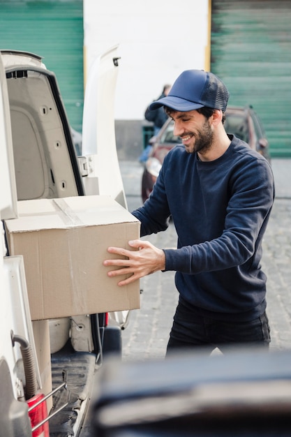 Glücklicher Lieferer, der Paket vom Fahrzeug löscht