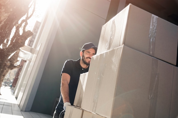 Foto glücklicher lieferer mit paketen auf bürgersteig