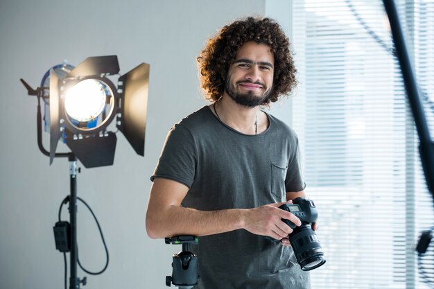 Glücklicher männlicher Fotograf, der im Studio steht