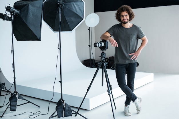 Glücklicher männlicher Fotograf, der im Studio steht