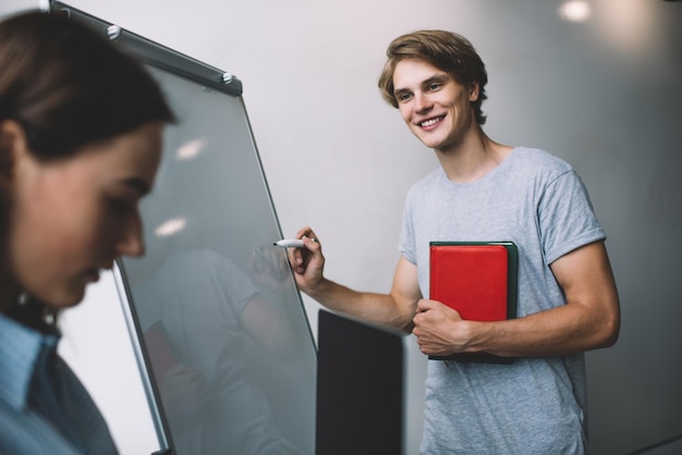 Foto glücklicher männlicher mentor, der informationen zur verwendung mit startup-projekten erklärt, die in der werkstatt stehen