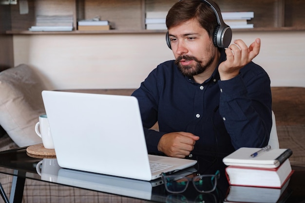 Glücklicher männlicher Online-Lehrer trägt Kopfhörer, spricht Videoanrufe an