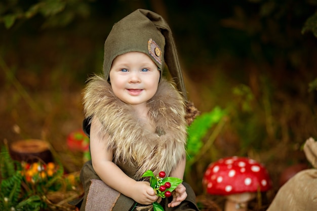 Glücklicher märchenhafter Babygnomjunge, der im Wald spielt und geht, Pilze pflückt, Äpfel isst