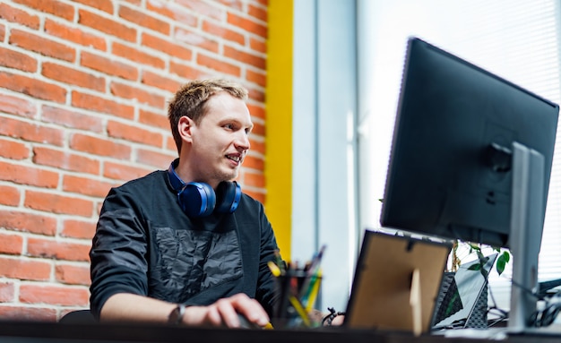 Glücklicher Mann, der am Schreibtisch im Büro sitzt