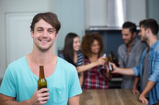 Glücklicher Mann, der Bierflasche während Freunde hält