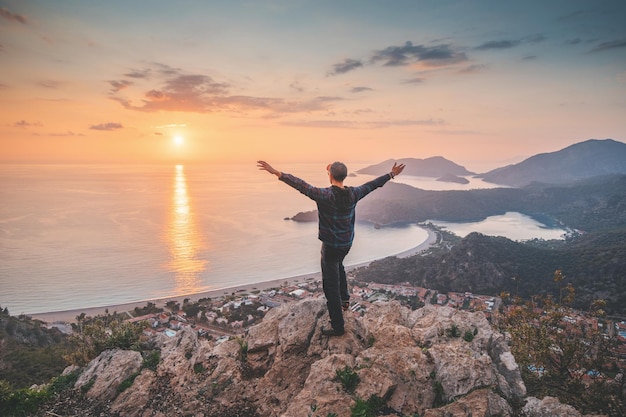 Glücklicher Mann, der den Blick auf einen malerischen Sonnenuntergang über der Stadt Ölüdeniz in der Türkei bewundert Lykischer Weg Reisesehenswürdigkeiten