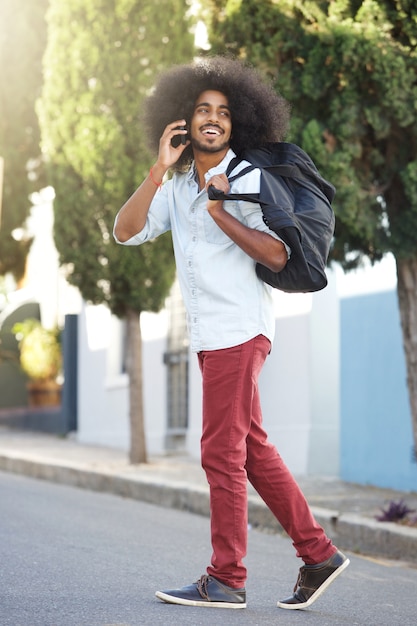 Glücklicher Mann, der draußen mit Telefon und Tasche geht