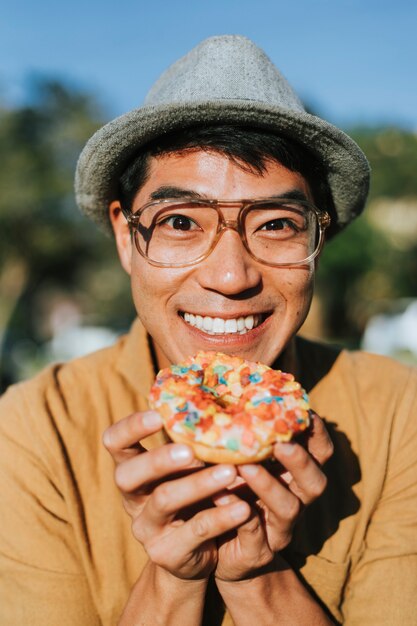 Glücklicher Mann, der einen Donut hat