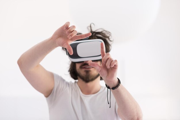 Glücklicher Mann, der Erfahrungen mit VR-Headset-Brillen der virtuellen Realität macht, isoliert auf weißem Hintergrund