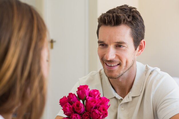 Glücklicher Mann, der Frau mit Blumen betrachtet