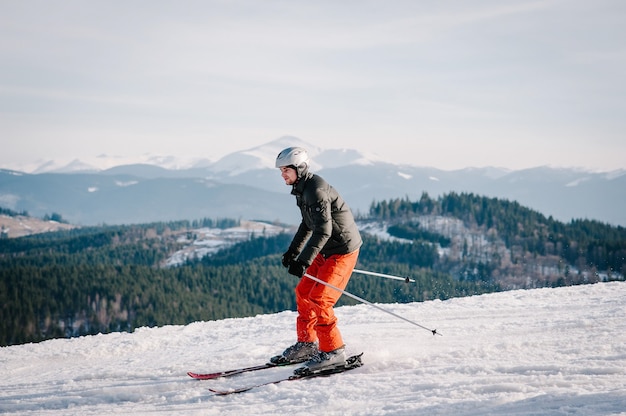 Glücklicher Mann, der in den schneebedeckten Bergen Ski fährt