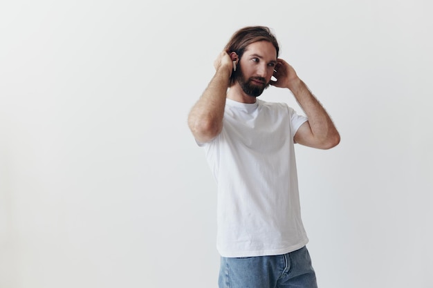 Glücklicher Mann, der Musik hört und in einem weißen T-Shirt auf weißem Hintergrund lächelt