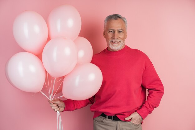 Glücklicher Mann, der rosa Luftballons hält