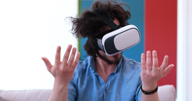 glücklicher Mann, der zu Hause Erfahrungen mit der VR-Headset-Brille der virtuellen Realität sammelt