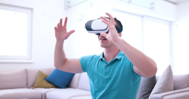 glücklicher Mann, der zu Hause Erfahrungen mit der VR-Headset-Brille der virtuellen Realität sammelt