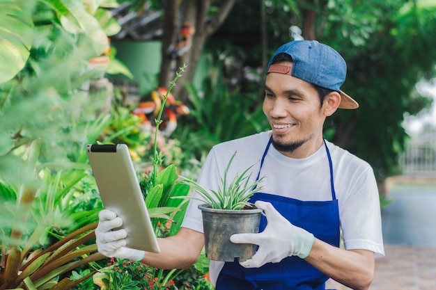 Glücklicher Mann Gartenladenbesitzer verwenden Tablet-Verkauf online kleine Blumen im Internet-Shop