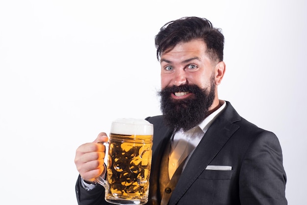 Glücklicher Mann im klassischen Anzug, der Bier trinkt Bärtiger Kerl im Business-Outfit sieht glücklich und zufrieden aus Porträt des Mannes mit angehobenem, hohem Glas Bier auf Weiß