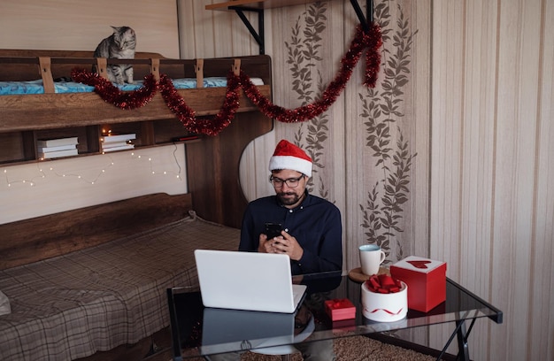 Glücklicher Mann macht einen Kauf im Internet über ein Telefon Viel Landschaft für das neue Jahr