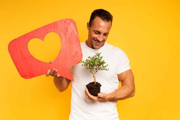 Glücklicher Mann mag einen kleinen Baum, der bereit ist, gepflanzt zu werden. Konzept der Aufforstung