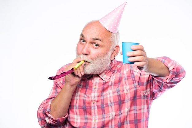 Glücklicher Mann mit Bart Ruhestandsfeier Mann hält Partykegelhut und pfeift alles Gute zum Geburtstag Firmenfeier Jahrestag Feiertagsfeier reifer bärtiger Mann mit pionted Hut Mehrfarbiger Spaß