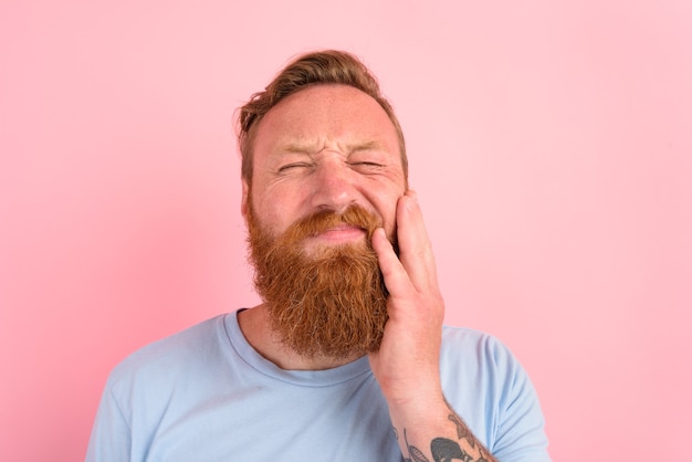 Glücklicher Mann mit hellblauem T-Shirt hat Schmerzen in den Zähnen