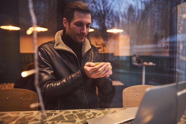 Glücklicher Mann mit Notizbuch, das mit Kaffee im Café ersetzt