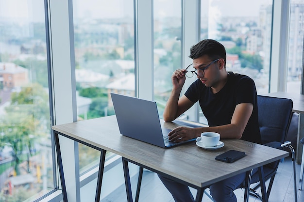 Glücklicher Mann mit optischer Brille zur Sehkorrektur auf der Suche nach lustigen Informationen in sozialen Netzwerken über eine drahtlose Verbindung zum Netbook-Technologiekonzept